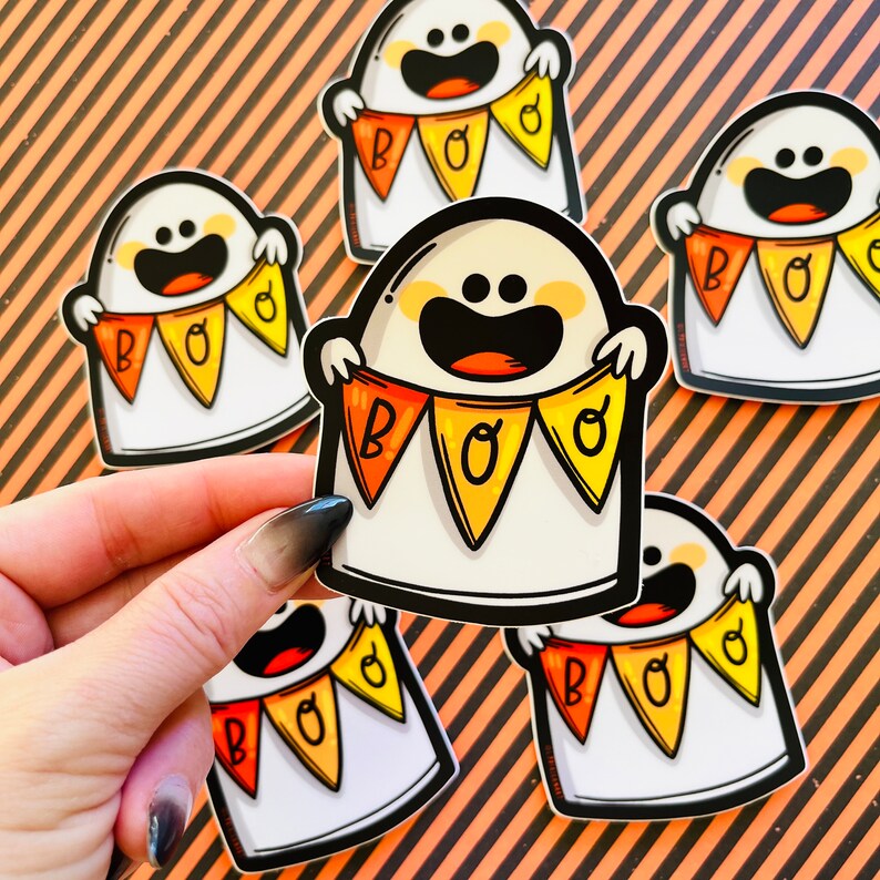 May include: Five white ghost stickers with orange and yellow bunting that reads "BOO" on each. The ghosts are smiling and have black eyes.
