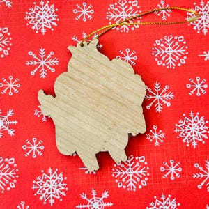 May include: A wooden Christmas ornament shaped like a cartoon character. The ornament is unpainted and ready to be decorated.