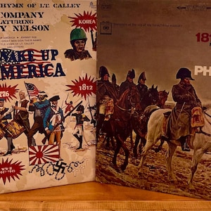 Puede incluir: Dos portadas de álbumes de discos de vinilo vintage. Una presenta el texto "Wake Up America" con ilustraciones de soldados y banderas. La otra portada del álbum tiene una pintura de soldados a caballo y el texto "1812 Overture".