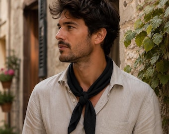May include: A beige long-sleeved button-down shirt with a textured fabric finish, featuring a solid black square neckerchief tied in a simple knot at the center of the collar. The shirt includes a single chest pocket and light-colored buttons.