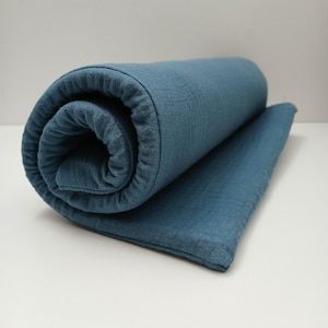May include: A rolled up blue muslin swaddle blanket. The blanket is soft and textured.