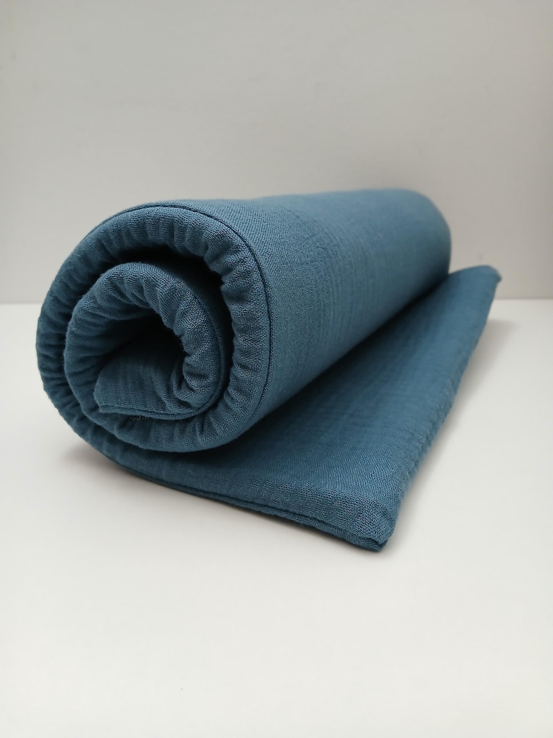 May include: A rolled up blue muslin swaddle blanket. The blanket is soft and textured.
