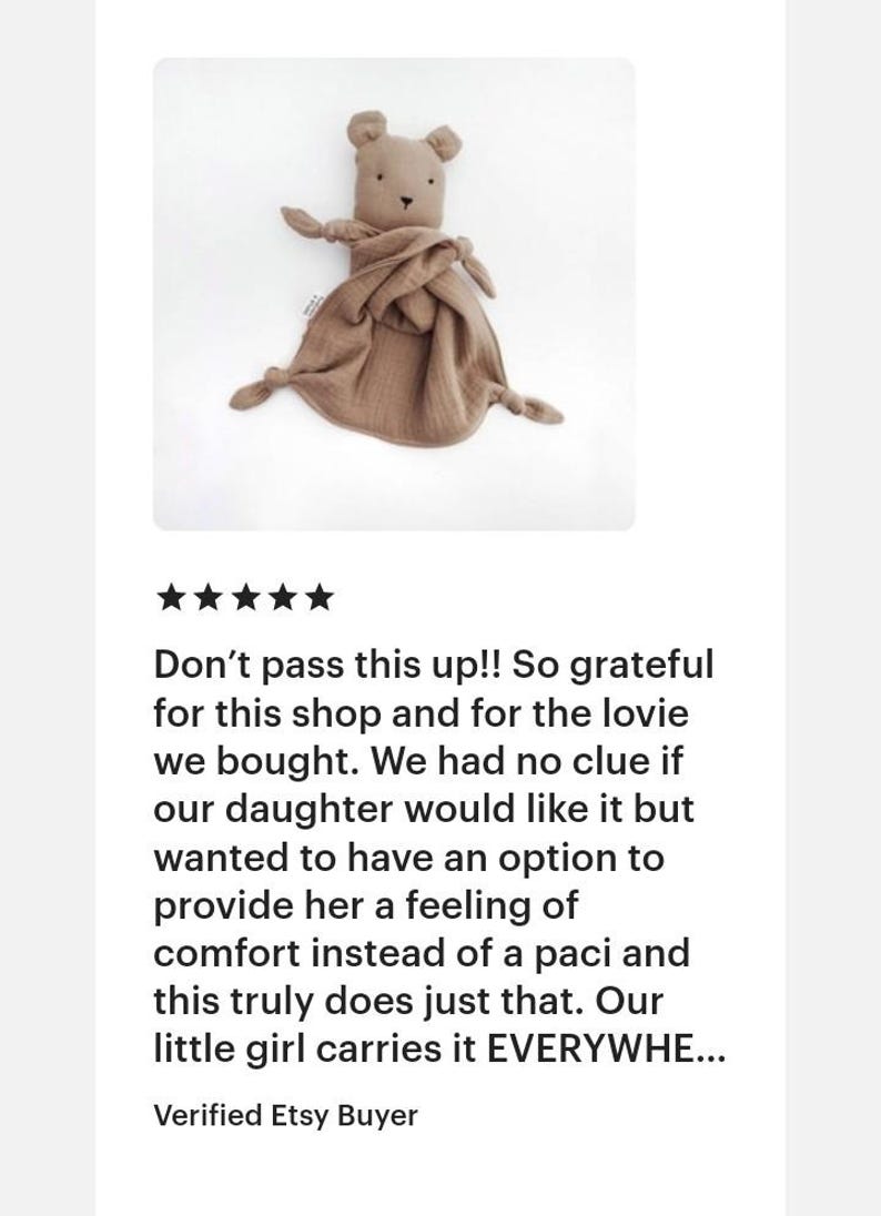 May include: A tan-colored bear-shaped security blanket made of soft, textured muslin fabric. The toy features a small bear head with embroidered eyes and nose, attached to a square piece of fabric with knotted corners for easy grasping.