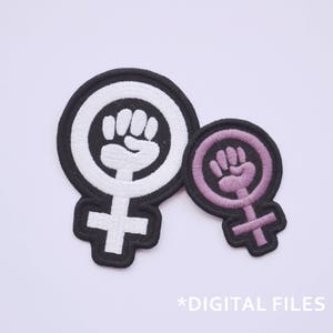 Pode incluir: Dois patches bordados para passar a ferro em forma de símbolo feminino com um punho levantado no seu interior. O patch maior é preto com um punho branco e o patch menor é roxo com um punho rosa.