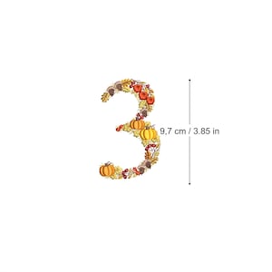 May include: A decorative number three shaped design composed of autumn elements including orange pumpkins, red apples, brown acorns, and yellow oak leaves. A vertical arrow indicates a height measurement of 3.85 inches for the digit.