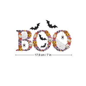 May include: Embroidered "BOO" design featuring a wreath of pumpkins, bats, spiders, and skulls. The design is approximately 7 inches wide.