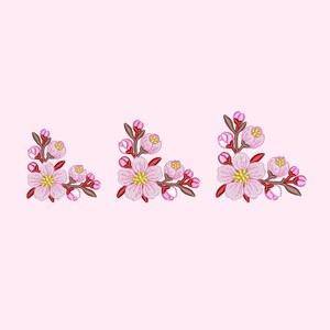 May include: Three embroidered pink and white flower clusters with red stems and green leaves. The flowers are arranged in a corner design.