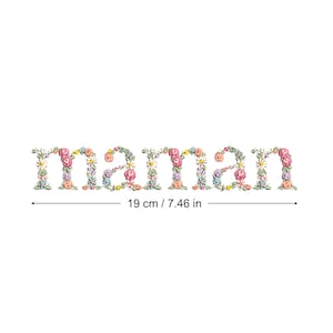 Puede incluir: La palabra "maman" (19 cm) está formada por flores coloridas. Las letras están llenas de una variedad de flores en tonos rosas, amarillos, azules y blancos, sobre un fondo blanco.