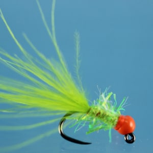 May include: A green and orange fly fishing lure with a bright green feather tail.