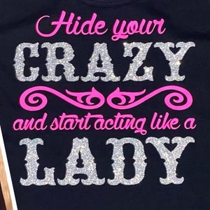 May include: Black t-shirt with the text "Hide your crazy and start acting like a lady" in pink and silver glitter.