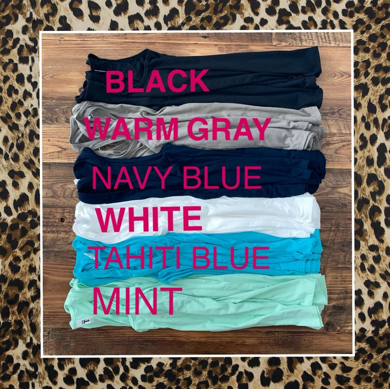 May include: Stack of six folded tank tops in various colours, including black, warm grey, navy blue, white, tahiti blue, and mint.