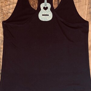 May include: Black tank top with a silver glitter guitar design on the back.