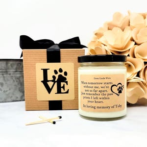 May include: A glass candle jar with a black lid and a beige label featuring the text: Dawn Candle Worx, When tomorrow starts without me, we're not so far apart. Just remember the paw prints I left within your heart. In loving memory of Toby.
