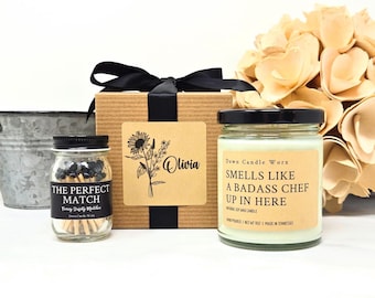 May include: A gift set featuring a candle, matches, and a decorative box tied with a black ribbon. The candle has a label that reads "Smells Like A Badass Chef Up In Here." The match jar reads "The Perfect Match."