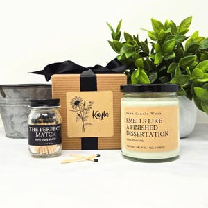 May include: A white ceramic mug with a black handle and the text "But First, Coffee" in a bold, black font. The mug is set against a blurred background, suggesting a cozy setting. The mug appears to be approximately 4 inches tall.