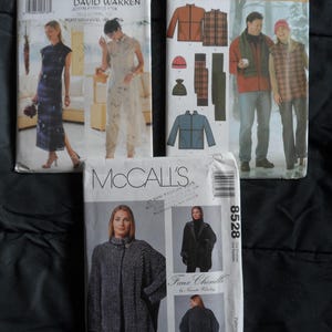 May include: Three sewing pattern envelopes. Butterick pattern 6057 features a woman in a long dress. Simplicity pattern 4803 shows a man and woman in jackets. McCall's pattern 8528 features a woman in a faux chenille cape.