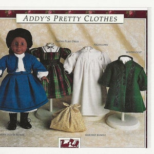 May include: A set of doll clothes for an 18-inch doll, including a blue school uniform, a plaid dress, a white nightgown, and a green winter coat. The doll clothes are displayed on mannequins and a small bag is included.