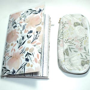 Puede incluir: Un juego de cuaderno y estuche con estampado floral. El cuaderno tiene un estampado floral en rosa suave, blanco y gris. El estuche es de color gris claro a juego con un diseño floral y cierre de cremallera.