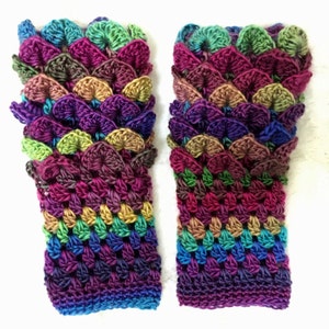 May include: A pair of colorful crocheted fingerless gloves with a scale pattern in shades of purple, green, brown, and blue.