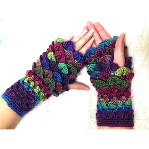 May include: A pair of colorful crocheted fingerless gloves with a textured, scale-like pattern. The gloves are made with a variety of shades of purple, green, blue, and brown yarn.