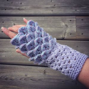 May include: Purple and blue crocheted fingerless gloves with a textured design. The gloves are made with a soft yarn and have a comfortable fit.