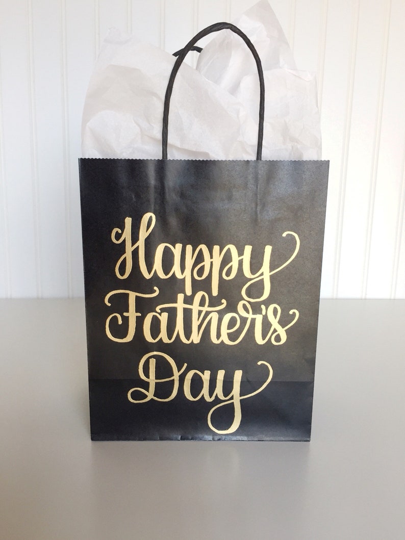 May include: Black paper gift bag with gold lettering that reads "Happy Father's Day".