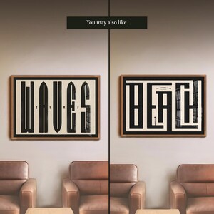 May include: Two framed prints with black and white typography on a cream background. The print on the left says "WAVES" and the print on the right says "BEACH". The prints are hanging on a wall in a room with two brown leather chairs and a coffee table.