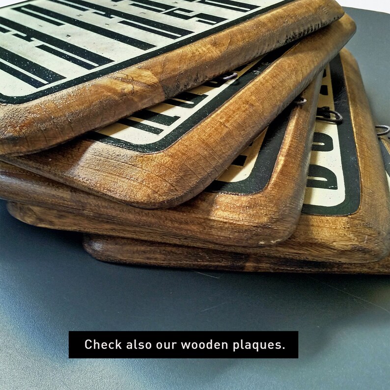 May include: A stack of four wooden plaques with black and white lettering. The plaques are stacked on top of each other, with the top plaque being the most visible. The plaques are made of a dark wood with a natural finish.