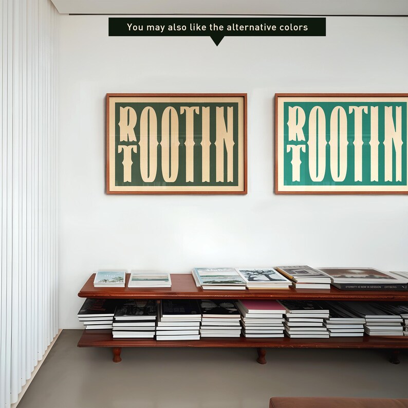 May include: Two framed prints with the word "ROOTIN" in a stylized font. The prints are in different colors, one with a green background and the other with a blue background. The prints are hanging on a white wall above a wooden shelf with books.
