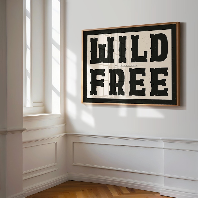 May include: A framed print with the words "WILD AND FREE" in bold black letters on a cream background.