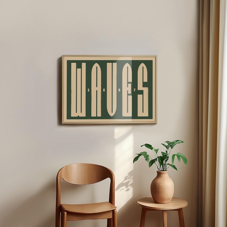 May include: A framed print with the word "WAVES" in a stylized font, with the word "SURF" written in smaller letters below. The print is on a green background with cream-colored letters. The print is hanging on a beige wall.