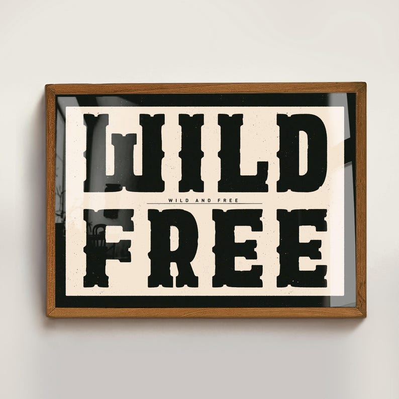 May include: A framed print with a black and white design. The text reads "WILD AND FREE" with the word "WILD" in large, bold letters and the word "FREE" in smaller, bold letters.