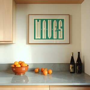 May include: A kitchen counter with a bowl of oranges, two bottles of wine, and a framed print with the word "WAVES" in a green and white color scheme.