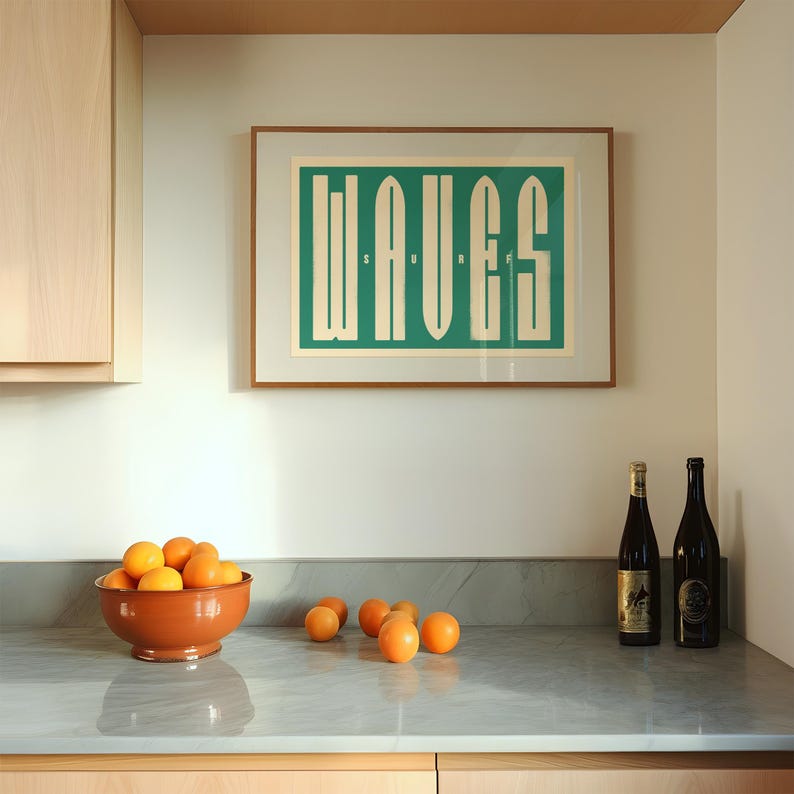 May include: A kitchen counter with a bowl of oranges, two bottles of wine, and a framed print with the word "WAVES" in a green and white color scheme.