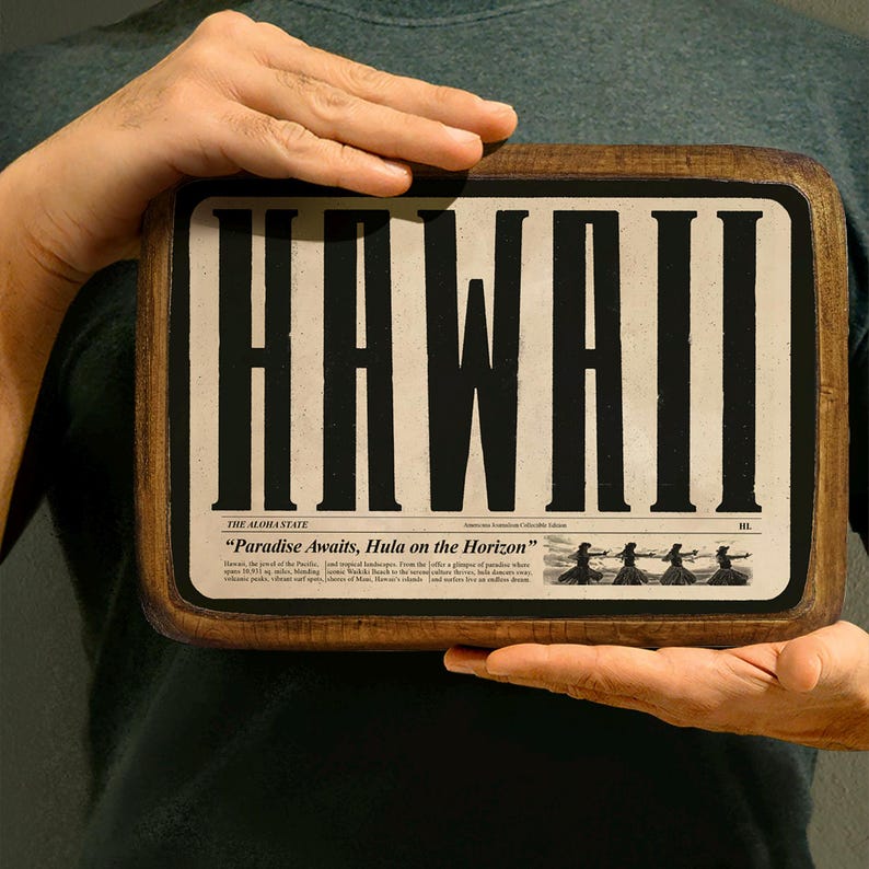 Op de afbeelding: Een houten bord met het woord "HAWAII" in grote zwarte letters. Het bord is versierd met een krantenontwerp en de tekst "The Aloha State "Paradise Awaits, Hula on the Horizon" en een illustratie van hula-dansers.
