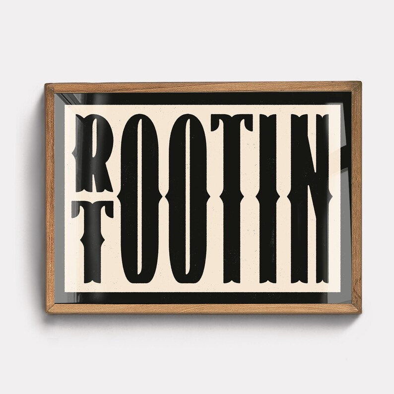 May include: A framed print with the word "ROOTIN'" in black text on a cream background. The frame is made of wood and has a dark brown finish.