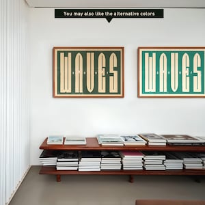 Puede incluir: Dos impresiones enmarcadas con la palabra "WAVES" en una fuente retro, una con fondo verde y la otra con fondo azul. Las impresiones est&aacute;n colgadas en una pared blanca sobre un estante de madera con libros.