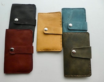 May include: Five leather wallets in different colors: black, brown, yellow, blue, and green. Each wallet has a flap with a snap closure.