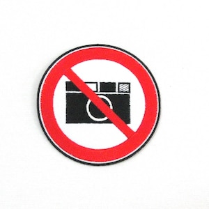 Puede incluir: Un círculo rojo con una línea roja diagonal que atraviesa un icono de cámara negro. El texto "No se permite la fotografía" no es visible en la imagen.