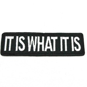 May include: Black embroidered patch with white text that reads "IT IS WHAT IT IS".
