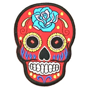 Może przedstawiać: Naszywka z czaszką cukrową w kolorze czerwonym, haftowana z niebieskim i białym kwiatem na czole. Czaszka ma żółte i czarne detale wokół oczu i ust.