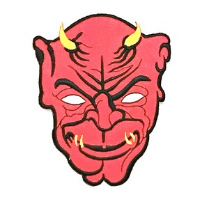 May include: Red devil mask with yellow horns and black eyes. The mask has a mischievous grin and two small yellow fangs.