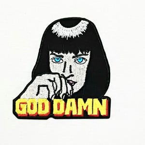 Op de afbeelding: Geborduurde patch met een gestileerd portret van een vrouw met zwart haar en blauwe ogen. De patch bevat de tekst "GOD DAMN" in gele letters met een rode rand, perfect voor jassen, tassen of andere stoffen items.