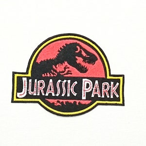 May include: A red and black embroidered patch with a dinosaur silhouette and the text "Jurassic Park" in white.
