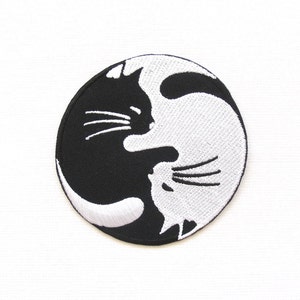 Puede incluir: Parche bordado en blanco y negro de dos gatos que se miran en un diseño yin yang.