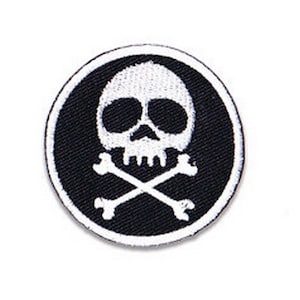May include: A black and white embroidered patch with a skull and crossbones design. The skull is white with black eyes and a black nose. The crossbones are white.