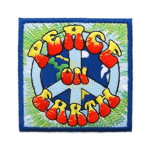 Può includere: Una toppa ricamata blu, verde, gialla e rossa con un simbolo di pace e le parole "Peace on Earth".