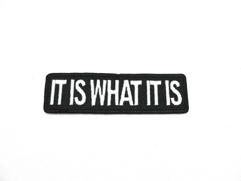 May include: Black embroidered patch with white text that reads "IT IS WHAT IT IS".