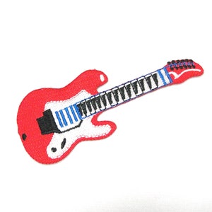 Puede incluir: Guitarra eléctrica roja con una golpeador blanco y rayas negras y azules en el diapasón. La guitarra está bordada sobre un fondo blanco.