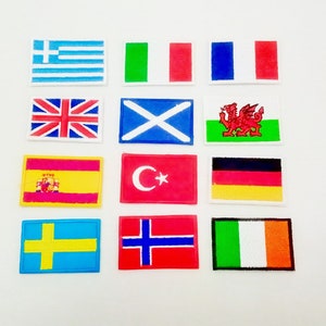May include: A collection of 12 embroidered iron-on patches featuring flags from different countries. The flags include Greece, Italy, France, United Kingdom, Scotland, Wales, Spain, Turkey, Germany, Sweden, Norway, and Ireland.